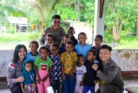 Anak-anak Kampung Ansudu tersenyum ceria saat menerima bingkisan makanan dari Satgas Damai Cartenz. Kehadiran polisi disambut hangat warga, Sabtu (2/8/2025).