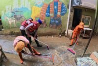 Personel Ditpolairud Polda Metro Jaya membantu warga Kampung Pulo bersihkan rumah dan saluran air usai banjir, Selasa (5/8/2025).