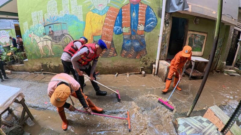 Personel Ditpolairud Polda Metro Jaya membantu warga Kampung Pulo bersihkan rumah dan saluran air usai banjir, Selasa (5/8/2025).