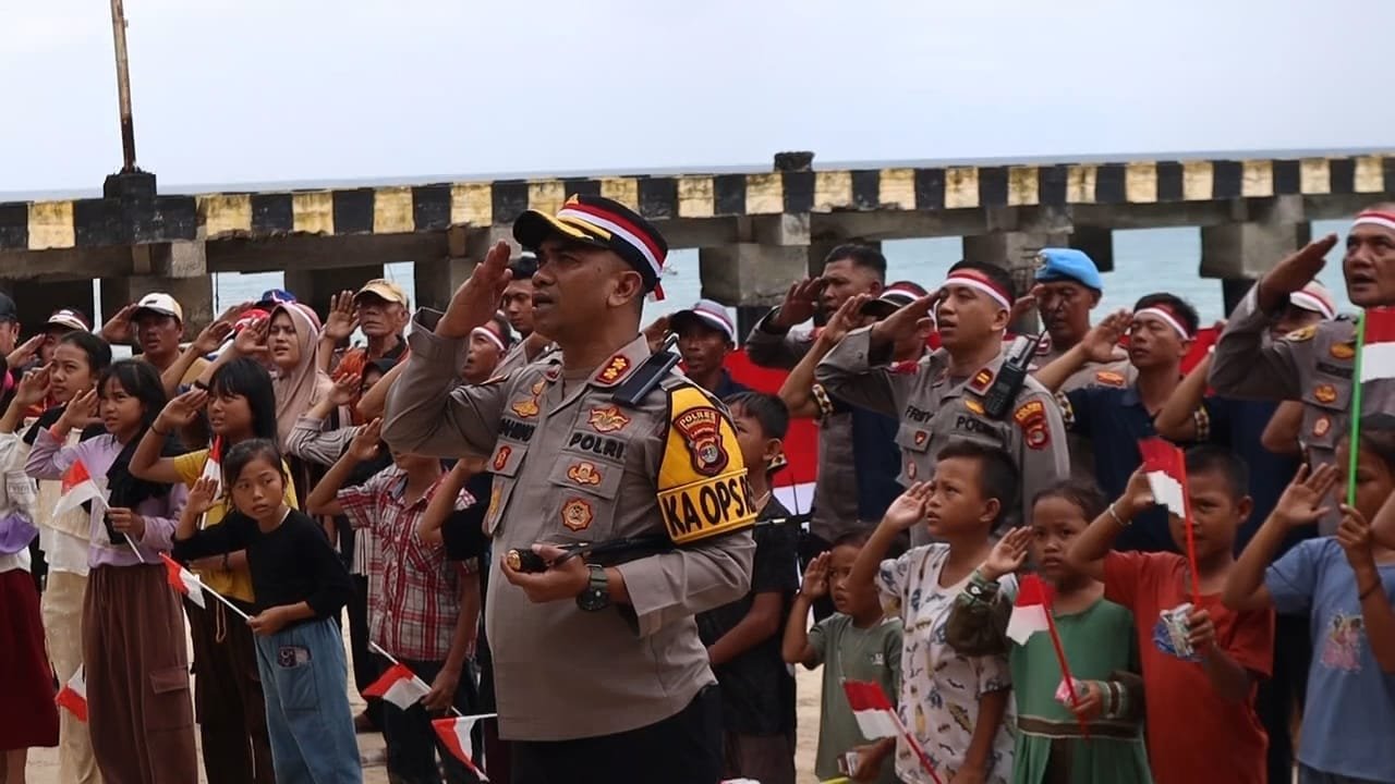 Kapolres Tanggamus AKBP Rahmad Sujatmiko bersama warga Pulau Tabuan mengibarkan bendera. Dok-Humas Polres Tanggamus)